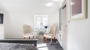 A modern hotel room with a bed, a glass-top table with chairs, a window, and a door. - The Secret: Stylish and Spacious En Suite Bathroom (Blandford Forum)