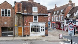 A traditional brick building with a sign reading "BARBER SHOP" on the ground floor. - The Secret: Stylish and Spacious En Suite Bathroom (Blandford Forum)
