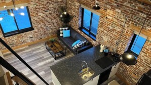 A modern kitchen with a large island, a built-in oven, and a sink. - Arch Building Lofts - Unit 6 (Redmond)