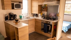 A compact kitchen with a microwave, coffee maker, toaster, and stove. - FAMILY MOBILHOME 6/8 pers COMFORTABLE AND AIR CONDITIONED (Veuzain-sur-Loire)
