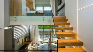 A modern interior with a glass staircase leading to a living area with a view. - Malia Palace by Luxury Living Apartments (Hersonissos)