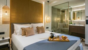 Une chambre d’hôtel moderne avec un grand lit, une douche en verre, une table de chevet en bois et un plateau de petit-déjeuner.