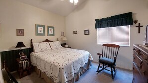 A bedroom with a bed, a rocking chair, a dresser, a nightstand, a lamp, a ceiling fan, and a window with blinds. - Spacious family suburban home (Colorado Springs)