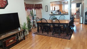 A dining area with a wooden table and chairs, a television, and a clock on the wall. - Spacious family suburban home (Colorado Springs)