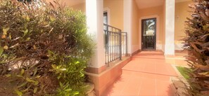 Stroll along the neatly trimmed hedges to the entrance of this building, featuring a columned doorway.