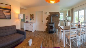 A cozy living room with a sofa, a wooden coffee table, a fireplace, and a dining area with chairs and a table.