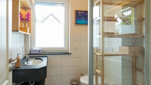 A bathroom with a black sink, white toilet, and a glass shower enclosure.