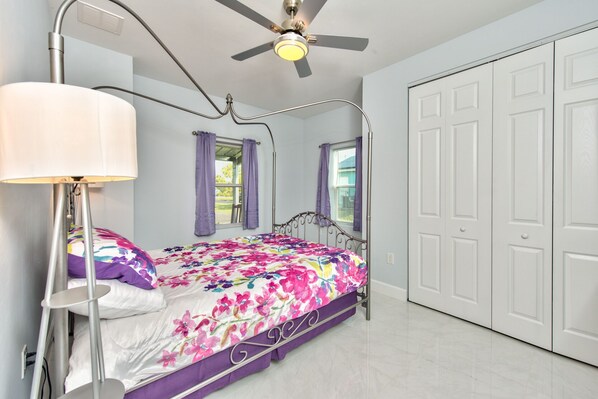 A bedroom with a bed, a ceiling fan, a window with purple curtains, and a white wardrobe. - New Barndominium! (Naples)