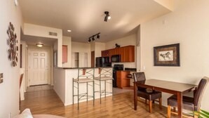 A modern kitchen with a central island, bar stools, and a dining table with chairs.