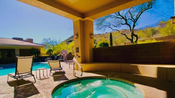 A pool area with lounge chairs and a hot tub.