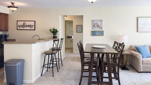 Una cocina moderna con barra, mesa de comedor con sillas y zona de estar con sofá.