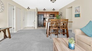 Amplia sala de estar con una mesa de comedor y sillas, una cocina al fondo y un rincón de descanso con sofá.