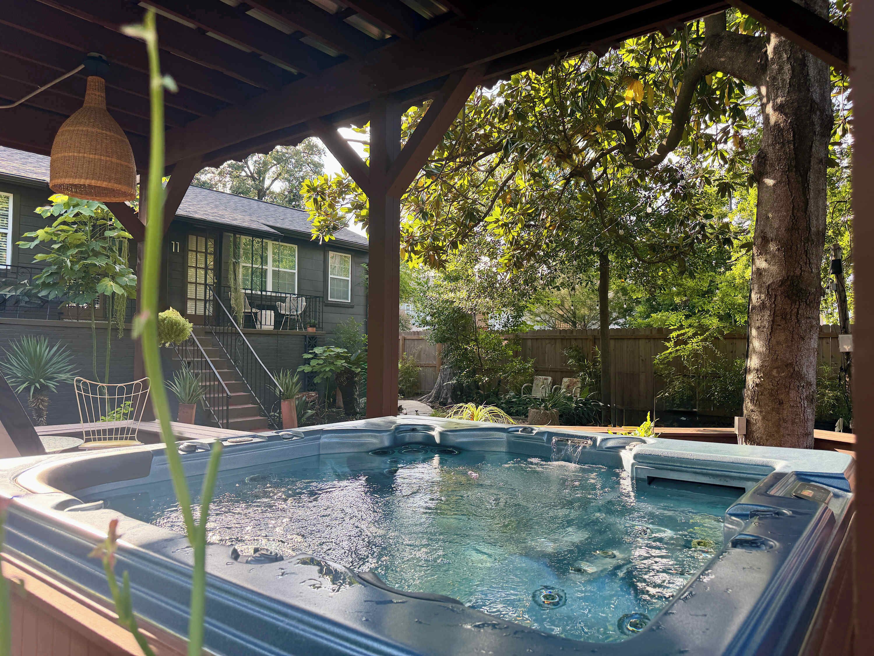 Ein Whirlpool unter einer Hollaube, im Hintergrund ein Haus.