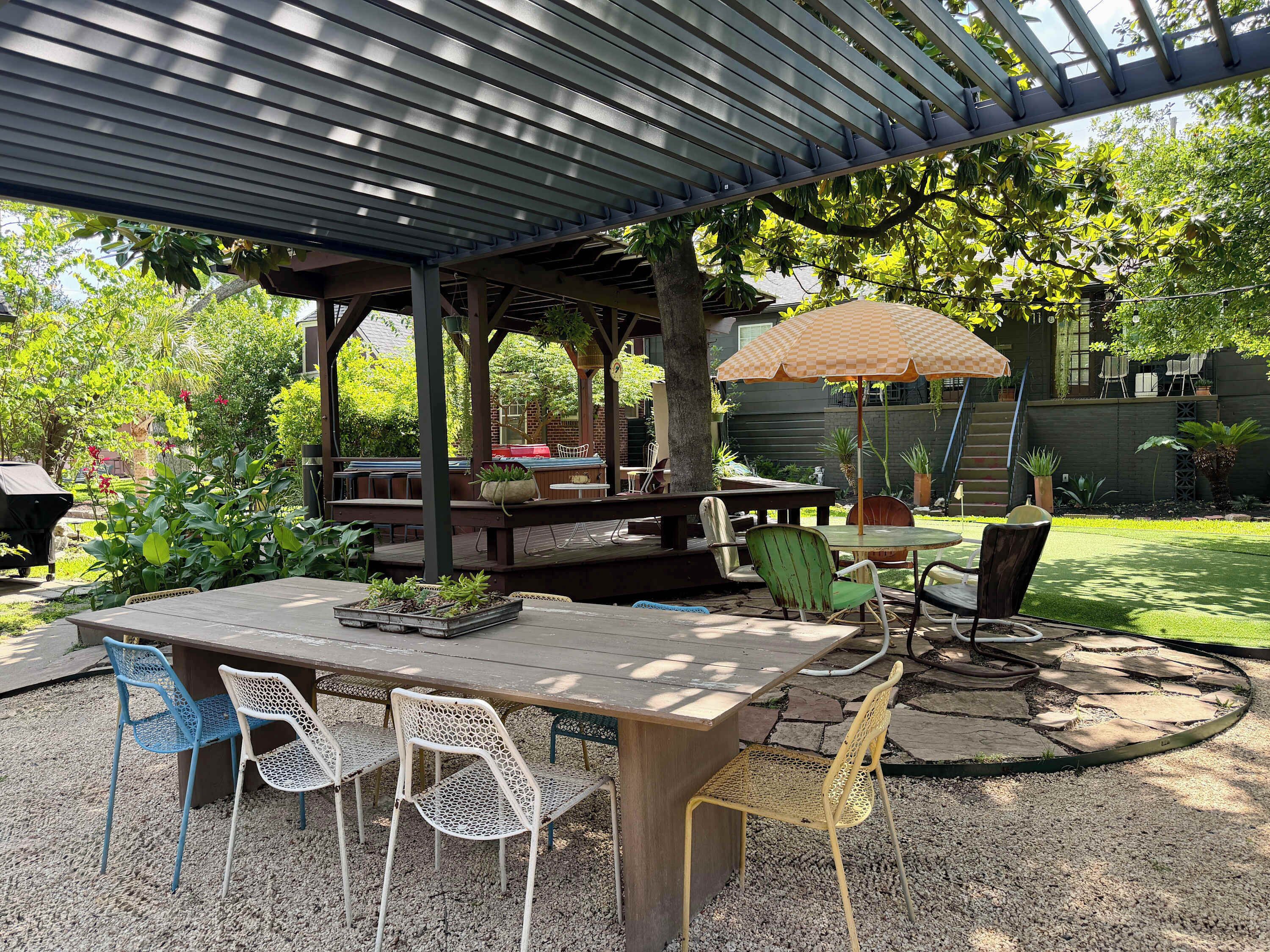 Zona de pati coberta amb taula i cadires, una barbacoa i un espai d'estar sota una pérgola.
