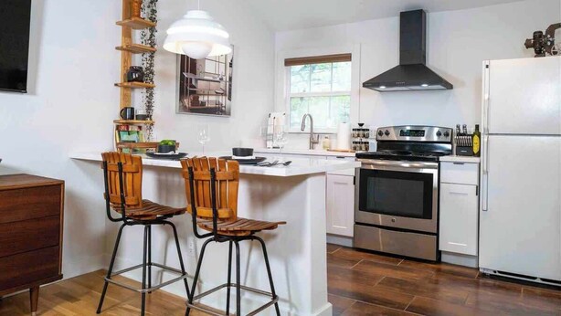 A modern kitchen with a central island, stainless steel appliances, and wooden bar stools.