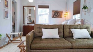 A cozy living room with a sofa, a small wooden table, and a hanging plant.
