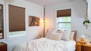 A bedroom with a bed, bedside tables, a lamp, and a window with blinds.