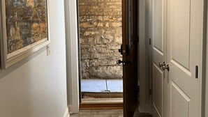 Un couloir doté d’un plancher en bois, d’un mur en pierre et d’une porte donnant sur une autre pièce.