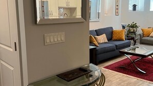 Un salon moderne avec une table basse en verre, un canapé orné de coussins jaunes et un tapis rouge.
