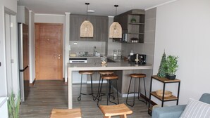 A modern kitchen with a central island, bar stools, and a blue sofa with a striped pillow.