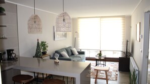 A modern kitchen with a central island, bar stools, a coffee machine, and a small Christmas tree.