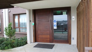 A wooden door with a glass panel, a doormat, and a sign indicating a smoking area.