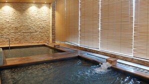 A spa area with a stone wall, wooden benches, and a water feature. - Blossom Hill Hotel Wuxi Yangshan (Wuxi)