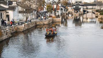 A traditional Chinese water town with a boat on the river, stone bridges, and traditional buildings.