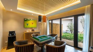 A modern living room with a pool table, comfortable seating, a flat-screen TV, and a large sliding glass door to the outdoors.