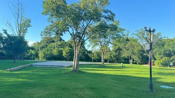 A park with a paved area, trees, and a utility pole with equipment.