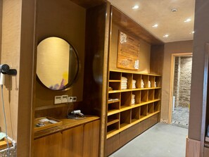 A hotel room with a wooden vanity, a mirror, a shelf with towels, and a wall-mounted sign. - Blossom Hill Hotel Wuxi Yangshan (Wuxi)