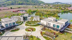 A modern building complex with a central courtyard, surrounded by landscaped gardens and a lake. - Blossom Hill Hotel Wuxi Yangshan (Wuxi)