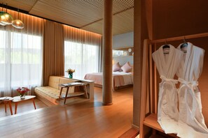 Una habitación de hotel moderna con sofá, cama, escritorio y perchero.