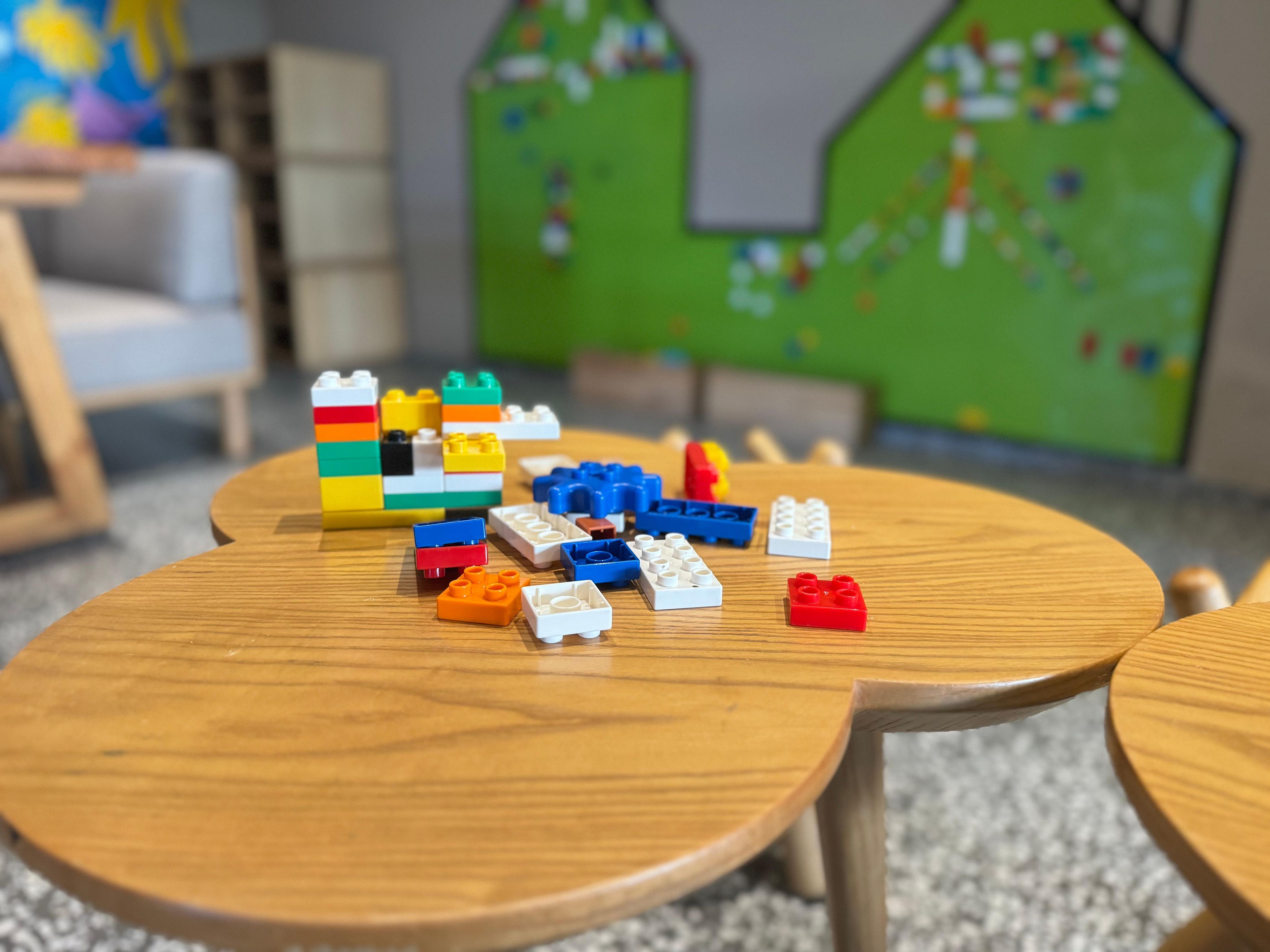 Uma mesa de madeira com blocos de construção coloridos espalhados.