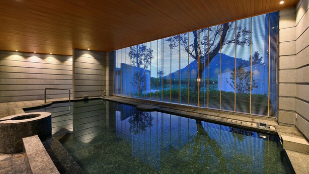 A modern indoor pool with a clear view of the outdoors through a large window, a wooden ceiling, and a stone wall. - Blossom Hill Hotel Wuxi Yangshan (Wuxi)