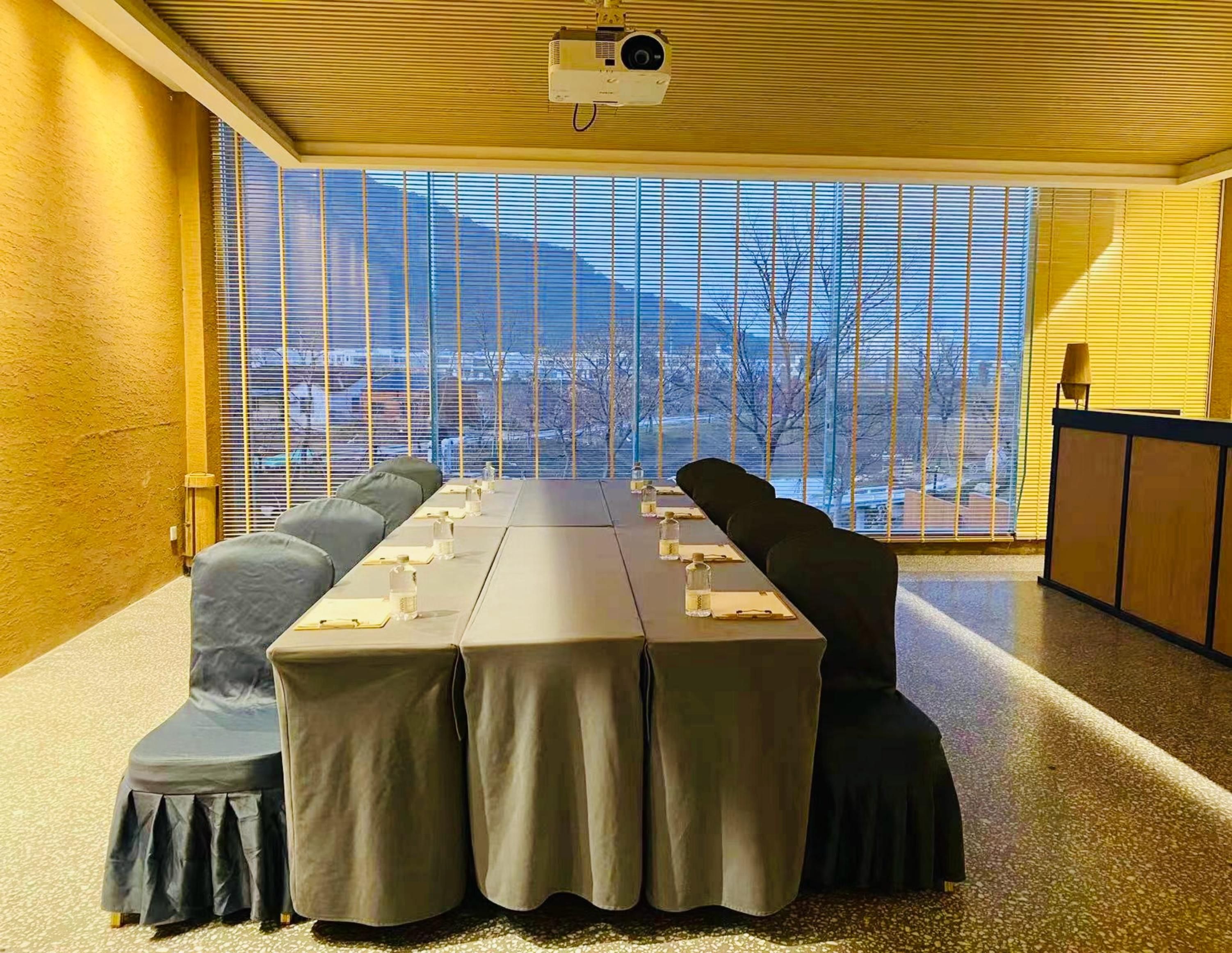 Une salle de conférence équipée d’une longue table, de chaises et d’un projecteur.