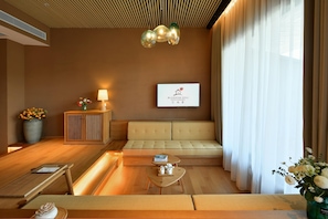 A modern hotel room with a sofa, a small table with a teapot, a lamp, and a sign on the wall. - Blossom Hill Hotel Wuxi Yangshan (Wuxi)