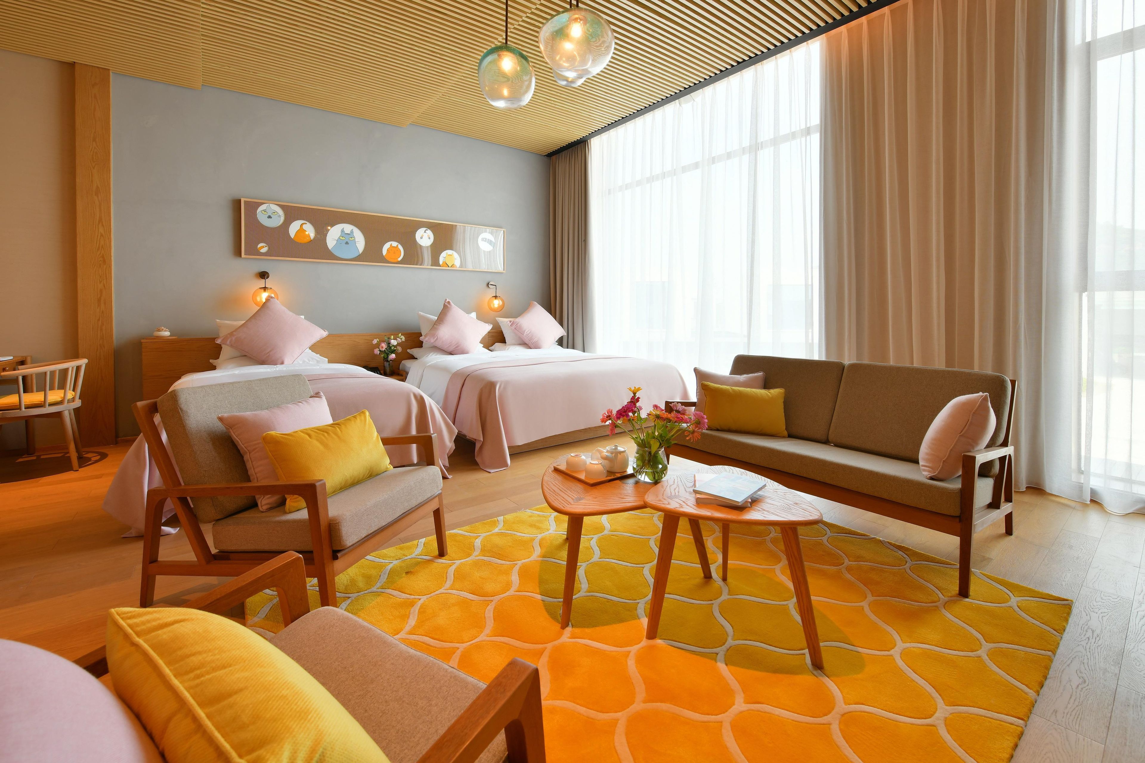 Ein Hotelzimmer mit Bett, Sofa, Sesseln, einem kleinen Tisch und einer Wanddekoration.