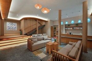 A modern interior with a sofa, a staircase, and a bookshelf. - Blossom Hill Hotel Wuxi Yangshan (Wuxi)