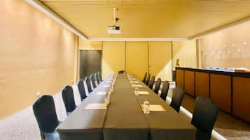 Una sala de conferencias con una larga mesa, sillas, un proyector y un dispensador de agua.