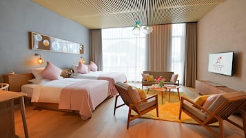 A hotel room with two beds, a sofa, a coffee table, and a TV.