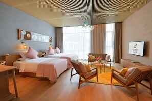 A hotel room with two beds, a sofa, a coffee table, and a TV. - Blossom Hill Hotel Wuxi Yangshan (Wuxi)