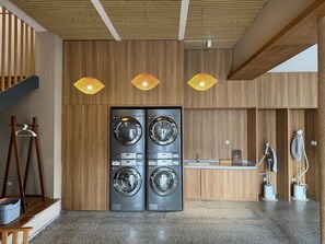 A modern laundry facility with two large front-loading washers, wooden paneling, and a small reception desk. - Blossom Hill Hotel Wuxi Yangshan (Wuxi)