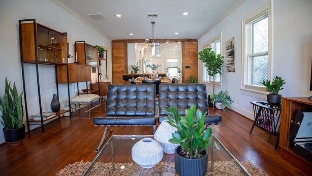 A modern living room with a leather sofa, wooden cabinets, and potted plants. - mid-century home w/detached apartment + hot tub (Houston)
