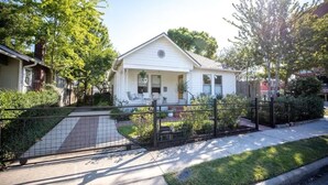 A single-story house with a front porch, a small garden, and a black metal fence. - mid-century home w/detached apartment + hot tub (Houston)