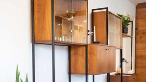 A modern interior with wooden shelving units, a clear glass partition, and a white cushioned bench. - mid-century home w/detached apartment + hot tub (Houston)