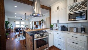 A modern kitchen with white cabinetry, stainless steel appliances, and a central island. - mid-century home w/detached apartment + hot tub (Houston)
