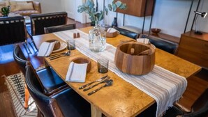 A dining area with a wooden table, chairs, a vase with greenery, and a bowl. - mid-century home w/detached apartment + hot tub (Houston)