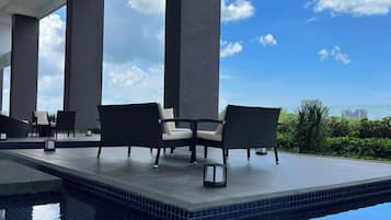 A rooftop infinity pool with lounge chairs and a clear view of the city skyline.
