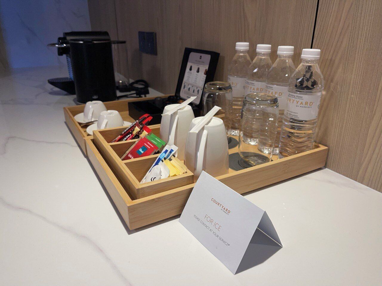 A hotel room's breakfast setup with a tray containing cups, utensils, and bottled water.